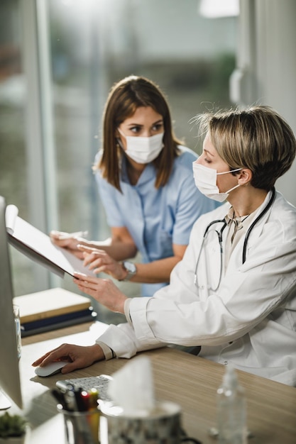 Foto de uma médica e uma jovem enfermeira trabalhando juntas no consultório do hospital.