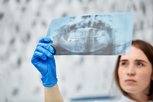 Foto de uma médica ou dentista olhando para um raio-x.