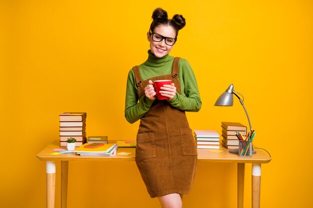 Foto de uma menina positiva com uma professora de ensino médio segurando uma caneca sobre um fundo de cor brilhante