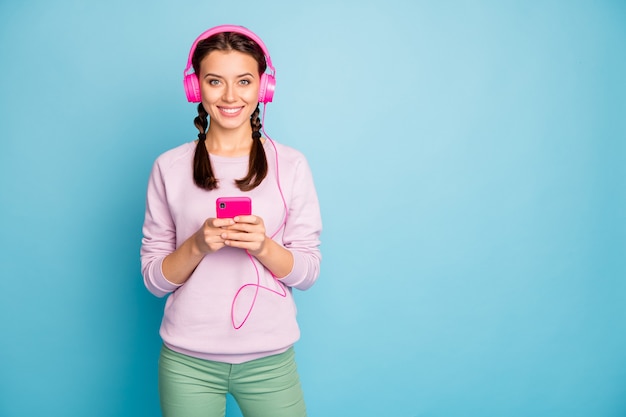 Foto de uma moça bonita segurando um fone de ouvido brilhante e legal nas orelhas, ouvindo rádio juvenil