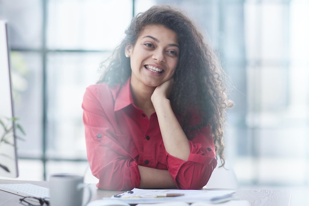 Foto de uma mulher alegre e simpática usando laptop e sorrindo enquanto está sentada