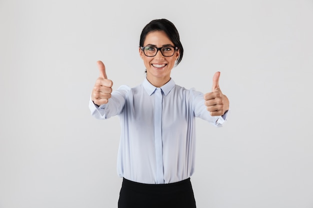 Foto de uma mulher de negócios feliz usando óculos, em pé no escritório, isolada sobre uma parede branca