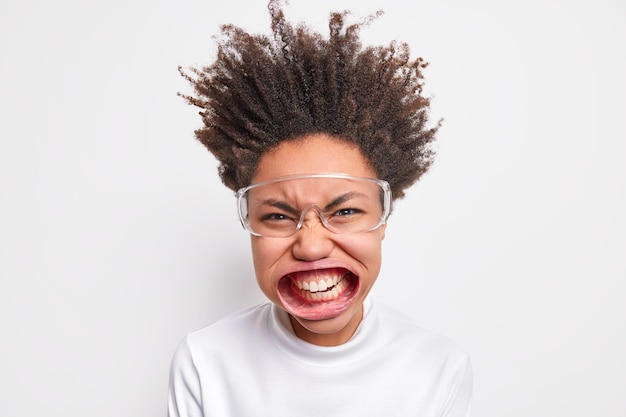 Foto de uma mulher louca emocional apertando os olhos, cerrando os dentes, abriu a boca expressando raiva e raiva sendo super louca usa óculos transparentes com gola alta