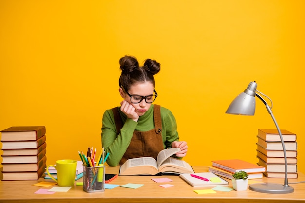 Foto de uma nerd entediada e inteligente lendo livro para aprender gramática, exame do último ano em fundo amarelo