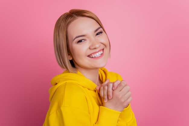 Foto de uma senhora alegre e muito confortável de mãos dadas com uma camiseta branca isolada em um fundo rosa