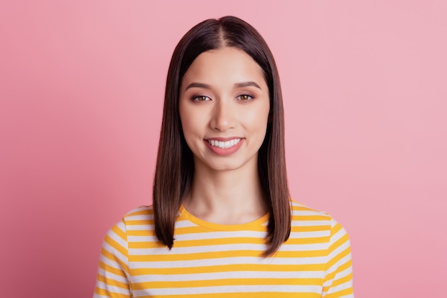 Foto de uma senhora alegre positiva olha para a câmera com um sorriso radiante dentuço no fundo rosa