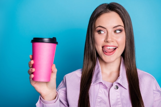 Foto de uma senhora encantadora segurando uma bebida quente para viagem em uma caneca rosa.