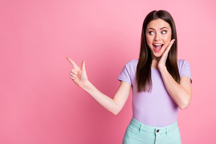 Foto de uma senhora engraçada muito chocada dedo direto espaço vazio novidade venda temporada de compras abrindo boca aberta animado desgaste casual violeta t-shirt calças isoladas fundo rosa cor pastel