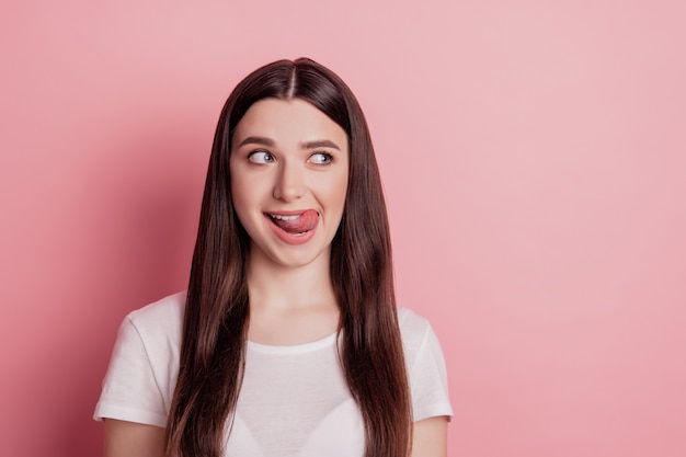 Foto de uma senhora incrível colocando a língua para fora da boca ver uma refeição saborosa lambendo os lábios isolado de fundo cor de rosa