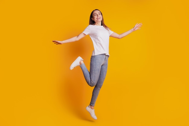 Foto de uma senhora louca e enérgica, divirta-se e use uma camiseta branca posando em um fundo amarelo