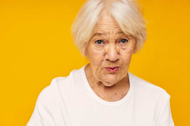 Foto de velha aposentada posando rosto careta alegria fundo amarelo