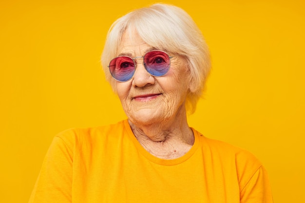 Foto de velhinha aposentada em uma camiseta amarela posando de fundo amarelo