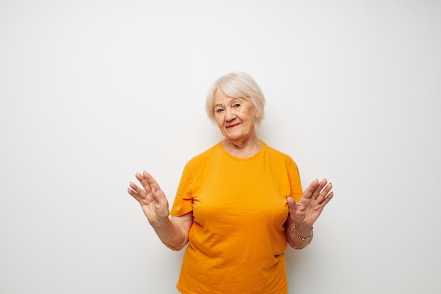 Foto de velhinha aposentada em uma camiseta amarela posando de fundo claro