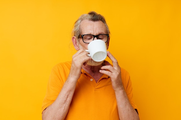 Foto de velho aposentado em um tiro monocromático de caneca branca de camiseta amarela