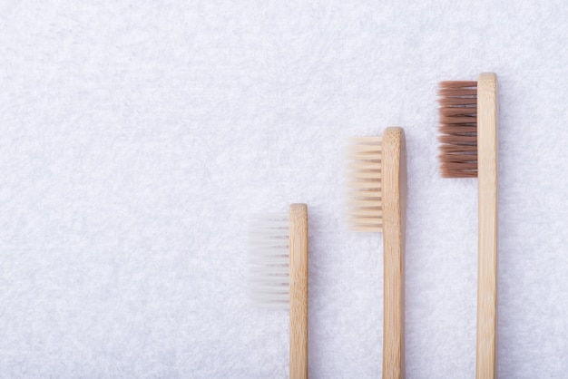 Foto de visão superior acima de três escovas de dente ecológicas de bambu isoladas em um fundo de toalha branca