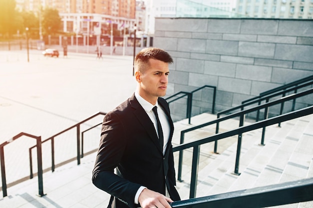 Foto de vista lateral do empresário confiante com roupa formal, olhando para longe enquanto descia as escadas