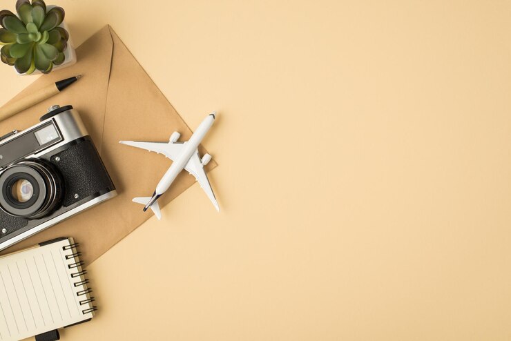Foto de vista superior da câmera de caderno de caneta de planta e modelo de avião em envelope de papel ofício em fundo bege isolado com copyspace
