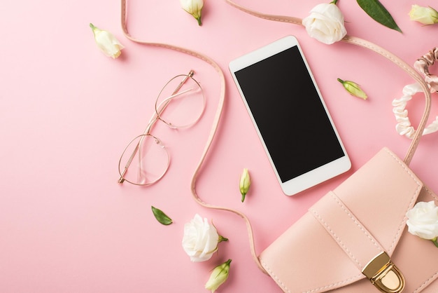Foto de vista superior da composição do dia da mulher bolsa de couro rosa óculos elegantes scrunchies de smartphone e botões de flores de genciana de pradaria branca em fundo rosa pastel isolado com espaço em branco