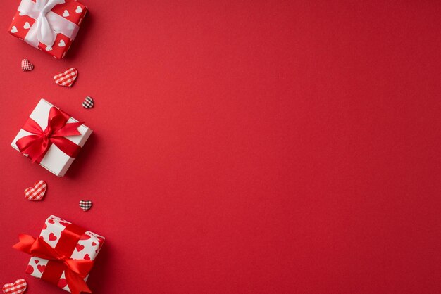 Foto de vista superior das decorações do dia de São Valentim, caixas de presente vermelhas e brancas e corações quadriculados em fundo vermelho isolado com espaço vazio