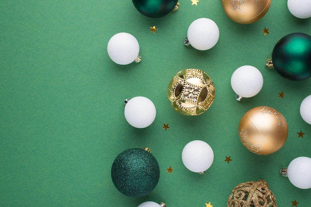 Foto de vista superior de bolas de árvore de natal douradas brancas e verdes e confetes de estrelas em fundo verde isolado com espaço em branco