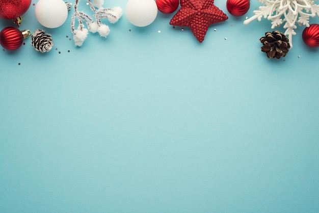 Foto de vista superior de bolas de decorações de árvore de natal branco e vermelho estrela floco de neve cones de pinho ramo nevado e lantejoulas em fundo azul pastel isolado com copyspace