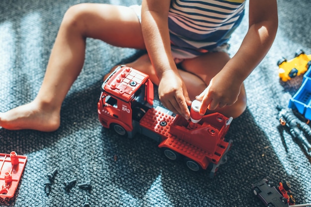 Foto de vista superior de um menino caucasiano brincando com um carro de construção no chão