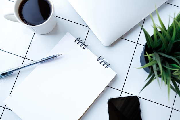 Foto de vista superior do local de trabalho com caneta de laptop na planta do notebook e xícara de café com espaço em branco