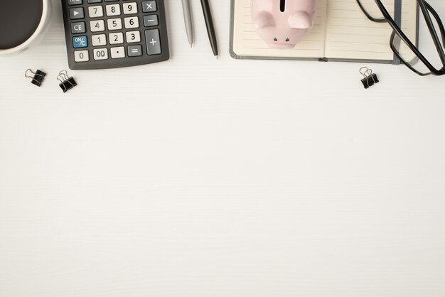 Foto foto de vista superior do local de trabalho de negócios com fichários de óculos canetas cofrinho na xícara de café do planejador e calculadora em fundo branco isolado com copyspace