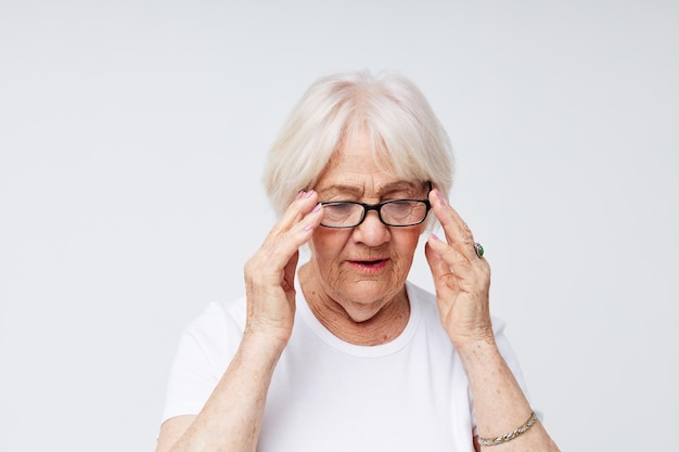 Foto der alten Dame im Ruhestand in lässigem T-Shirt und hellem Hintergrund der Brille