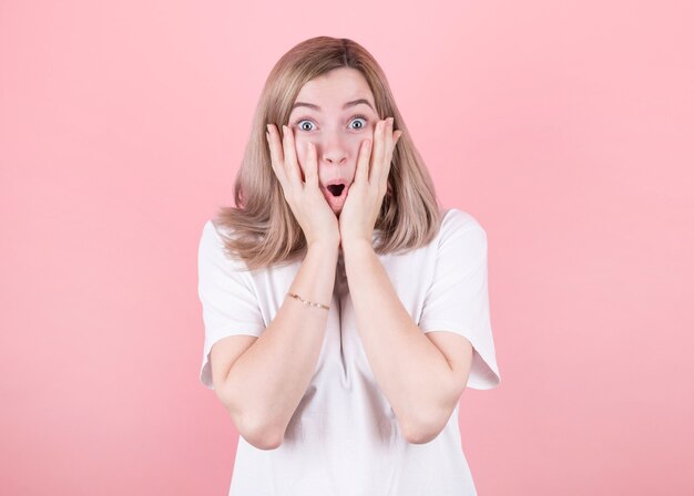 Foto der aufgeregten schreienden jungen Frau, die über rosa steht