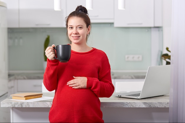 Foto der entspannten hübschen jungen Dame mit geschwollenem Bauch