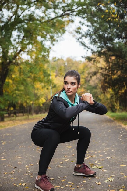 Foto der erstaunlichen jungen hübschen Fitnessfrau draußen im Park machen Übungen.