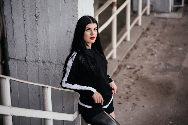 Foto der gesunden behinderten Frau in der Sportkleidung mit dem Prothesenbein, das an der Treppe steht und beiseite im Freien schaut