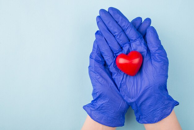 Foto der Hände in den Handschuhen, die kleines rotes Herz lokalisiert halten