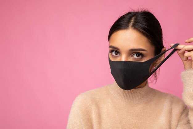 Foto der jungen attraktiven Frau mit handgemachter Baumwollstoff-Gesichtsmaske isoliert über bunter Hintergrundwand. Schutz vor COVID-19.