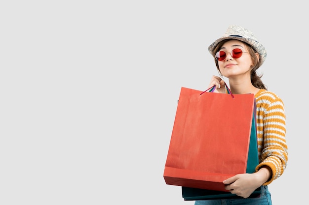 Foto der jungen Brunettefrau in der Sonnenbrille, die Einkaufstaschen hält. Foto in hoher Qualität