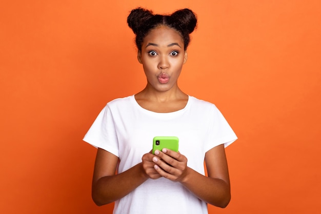 Foto der jungen charmanten Afrikanerin Chat Typ SMS-Nachricht Handy pralle Lippen isoliert über orangefarbenem Hintergrund