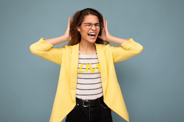 Foto der jungen emotional wütenden attraktiven brünetten lockigen Frau mit aufrichtigen Emotionen, die stylisch trägt