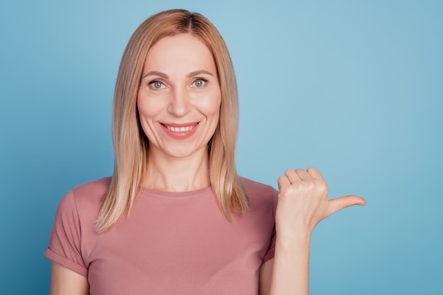 Foto der jungen Frau glückliches positives Lächeln zeigt Daumen leeren Raum Ad-Promo-Beratungswahl einzeln auf blauem Hintergrund an