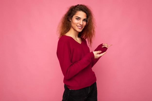 Foto der jungen glücklichen positiven lächelnden schönen brünetten gewellten Frau mit aufrichtigen Gefühlen tragend