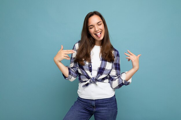 Foto der jungen positiven glücklichen lächelnden schönen Frau mit aufrichtigen Gefühlen, die stilvolle Kleidung tragen, lokalisiert über Wand mit Kopienraum und auf sich selbst zeigend.