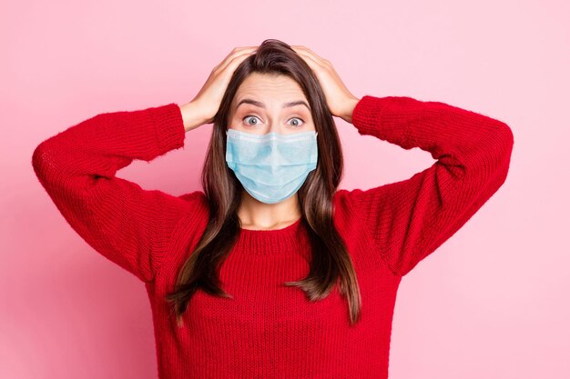 Foto der jungen schönen Dame, die den Kopf mit den Händen berührt, trägt eine blaue Gesichtsmaske isoliert rosafarbenem Hintergrund