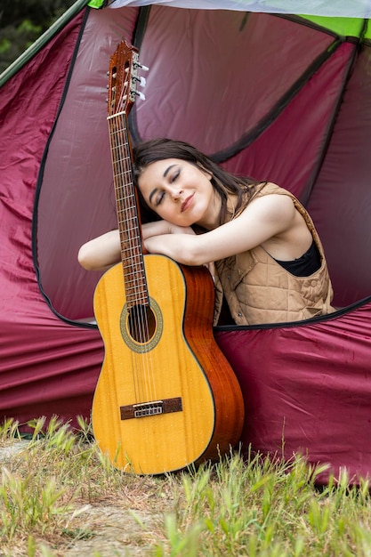 Foto der jungen schönen Dame legte ihren Kopf auf ihre Gitarre und schloss ihre Augen