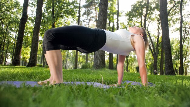 Foto der lächelnden Frau mittleren Alters, die Yoga Asana praktiziert. Persong, die in der Natur meditiert. Balance und Harmonie von Körper und Geist