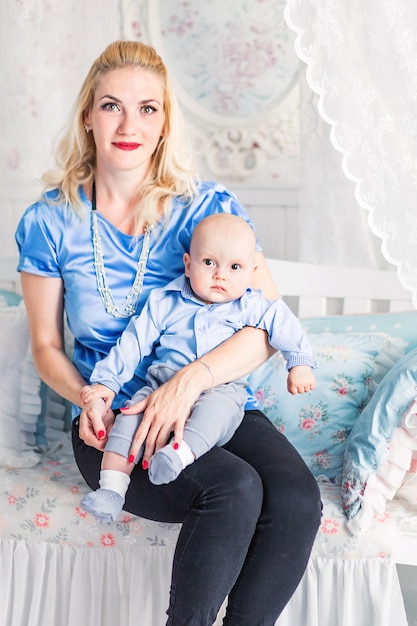 Foto der Mutter sitzt mit dem Kind im Kinderzimmer und schaut in die Kamera