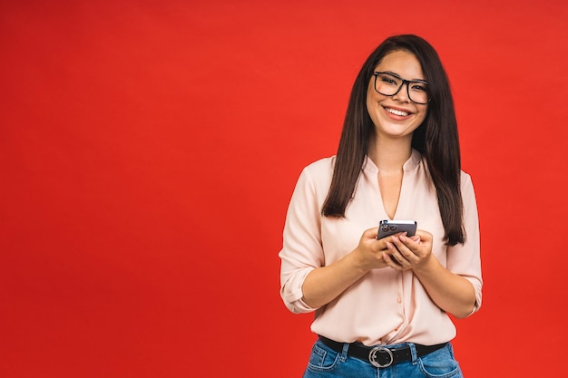 Foto der netten netten jungen Frau des schönen Geschäfts, die Handy lokalisiert über rotem Hintergrund verwendet Platz für Text