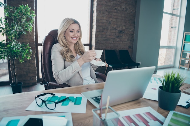 Foto der schönen Geschäftsdame, die Laptopbildschirm hält Kaffeetasse hält