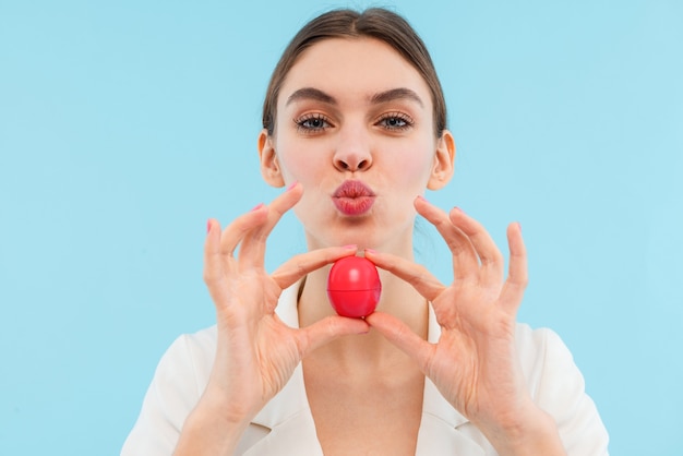 Foto der schönen jungen frau, die isoliertes halten des lippenbalsams aufwirft.