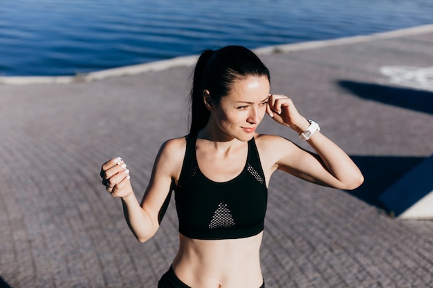 Foto der schönen jungen Sportfrau, die draußen Musik hört.