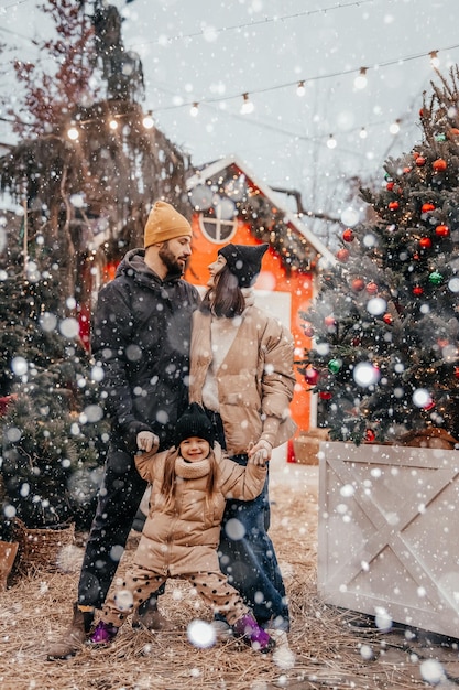 Foto der stilvollen Familie, Mama, Papa, Tochter, Huckepack, glückliches, positives Lächeln, schauen sich im Winterurlaub im Freien an